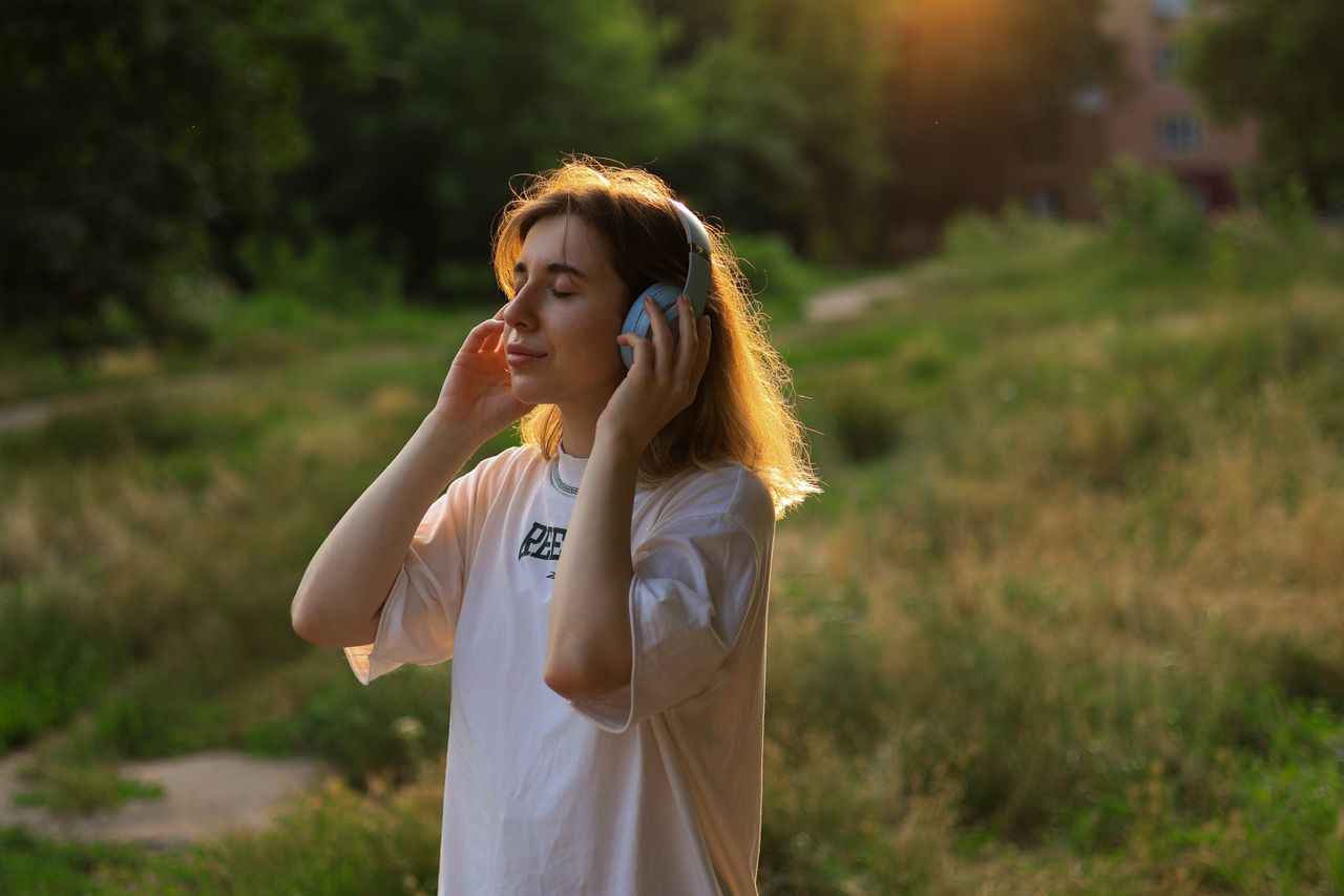 屋外でヘッドホンを使って音楽を聴く女性